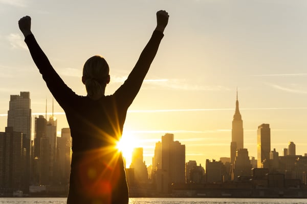 Man raising arms in front of city skyline