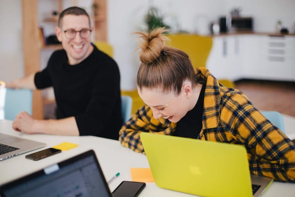 Two colleagues laughing at a desk